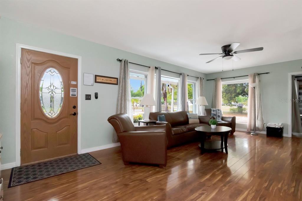 A living room features light green walls, hardwood floors, a brown leather sofa, and a front door — 305 BAKER AVENUE, CLEARWATER, FL