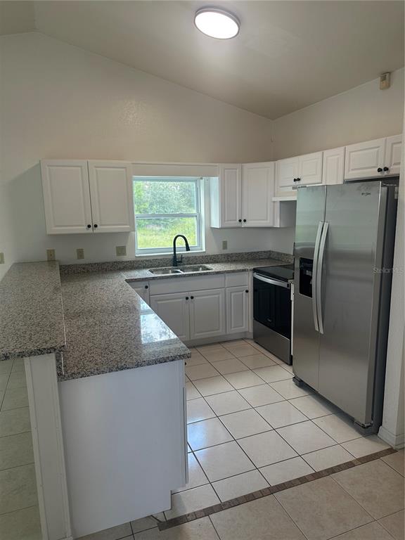 A kitchen with white cabinets, granite countertops, stainless steel appliances, and white tile flooring — 3909 SW 161ST LOOP, OCALA, FL