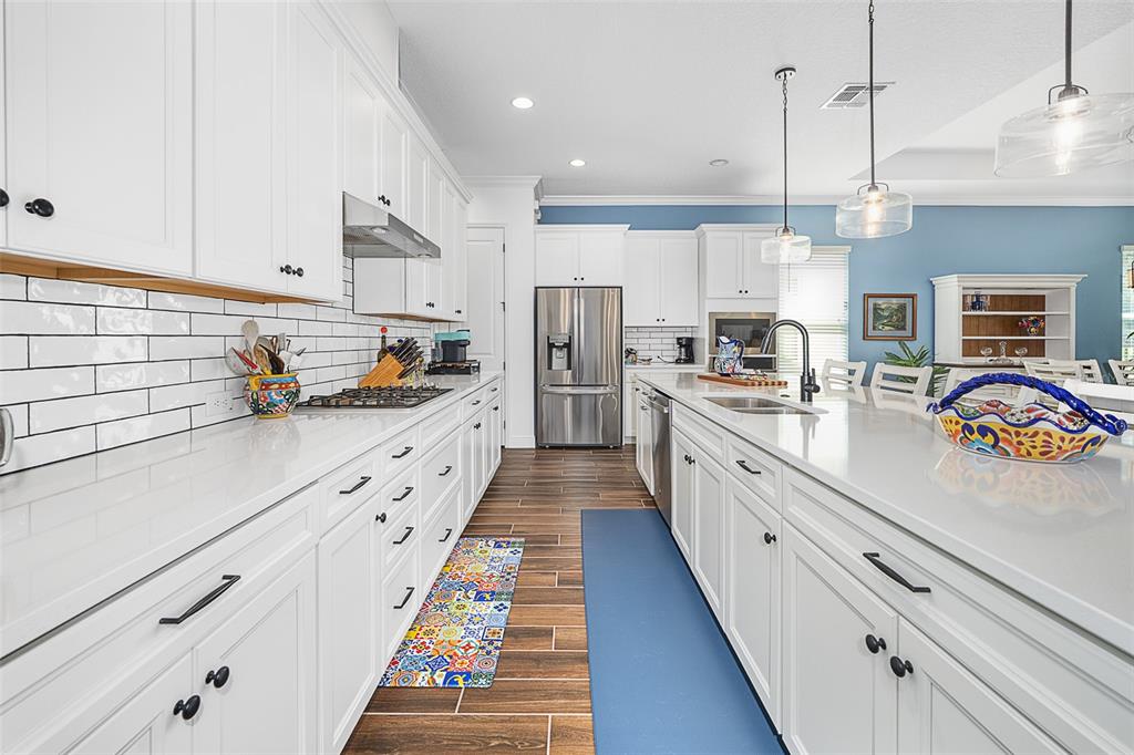 A bright kitchen features white cabinetry, quartz countertops, stainless steel appliances, and blue accent walls — 7748 FOUR SEASONS BOULEVARD, KISSIMMEE, FL