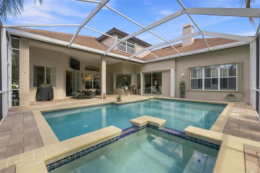 A screened-in patio features a swimming pool, a raised spa, and a covered seating area — 5091 JASMINE WAY, PALM HARBOR, FL