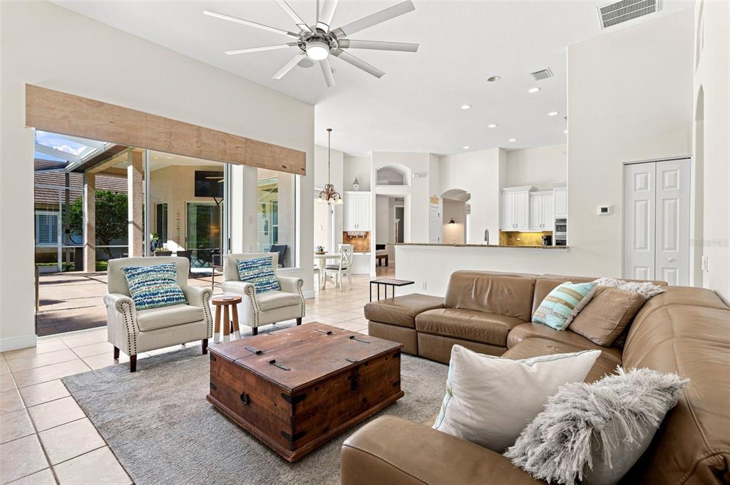 A living room with a brown sectional, wooden coffee table, and sliding doors to a patio — 5091 JASMINE WAY, PALM HARBOR, FL