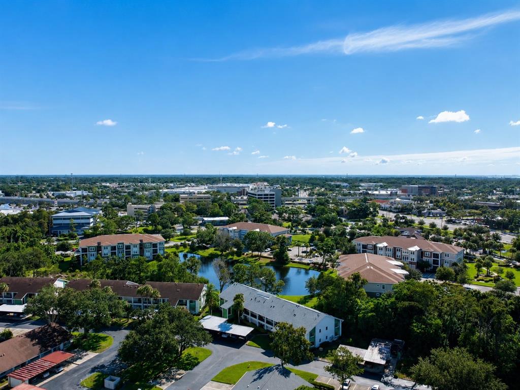 An aerial view shows apartment buildings surrounding a small pond in a suburban landscape — 2531 ROYAL PINES CIRCLE UNIT 23E, CLEARWATER, FL