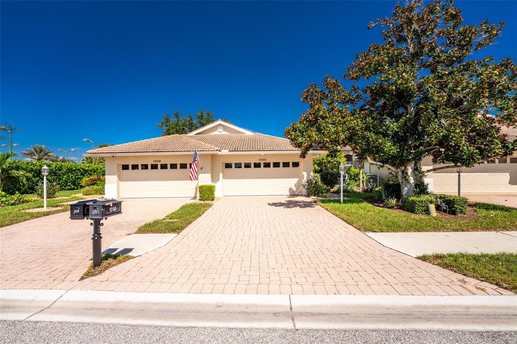 A single-story house with a two-car garage, a paved driveway, and a large tree — 1050 YOSEMITE DRIVE, ENGLEWOOD, FL