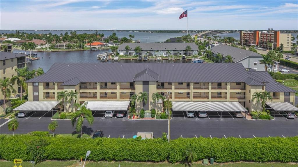 An aerial view of a multi-story apartment building with covered parking and a waterfront location — 4719 SE 17TH PLACE UNIT 105, CAPE CORAL, FL