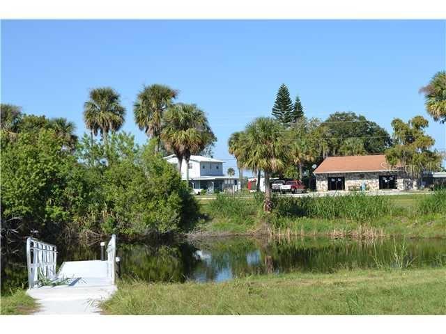 A small white dock sits on a pond in front of houses and palm trees — 6275 US-441 HIGHWAY SE, OKEECHOBEE, FL