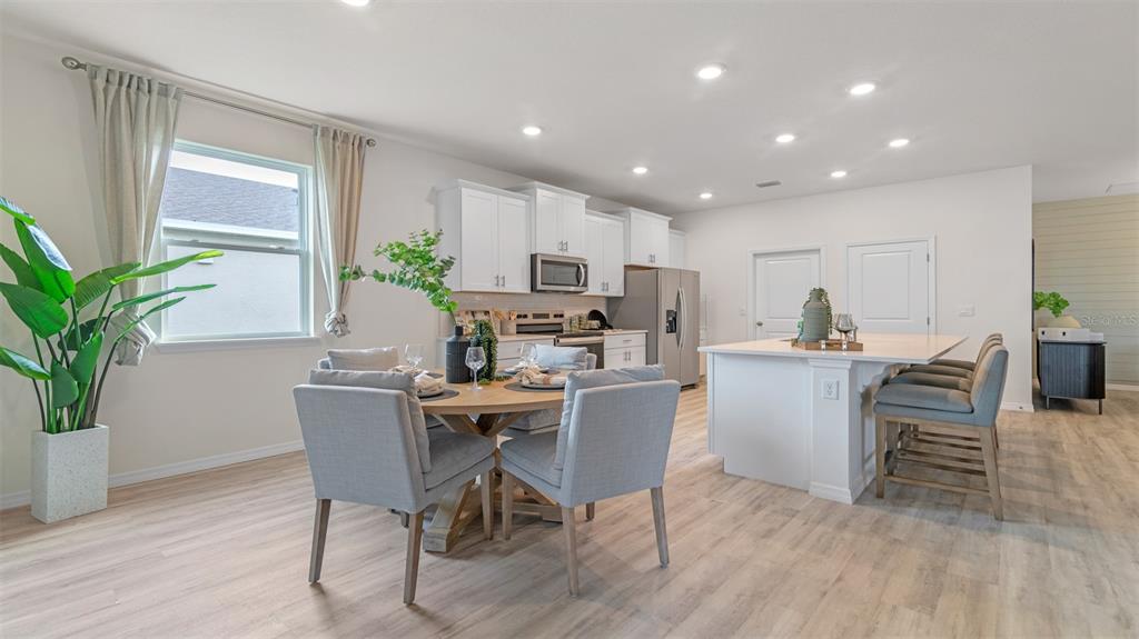 A kitchen and dining area with white cabinets, a central island, and light wood flooring — 3001 KINGSMAN TRAIL, ORMOND BEACH, FL