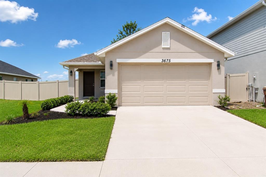 A tan one-story house with a two-car garage and a concrete driveway — 3675 SAGEFIELD DRIVE, HARMONY, FL