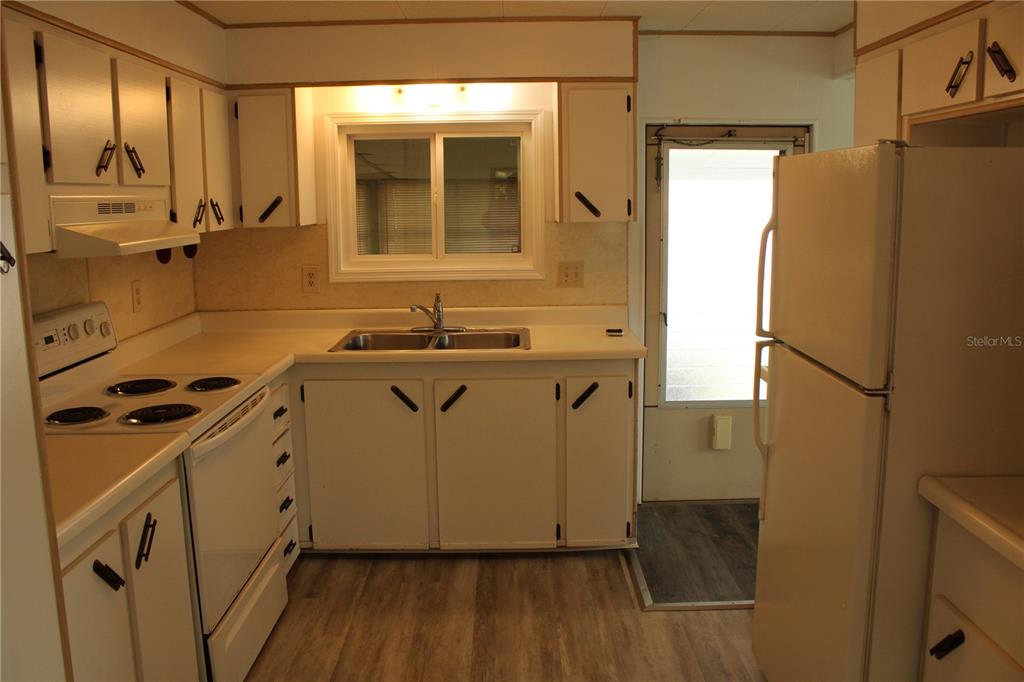 A kitchen features white cabinets, a double sink, a white stove, and a white refrigerator — 204 50TH AVENUE DRIVE W, BRADENTON, FL