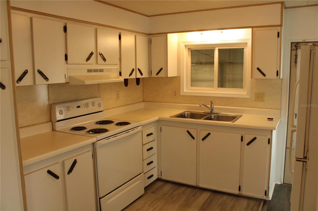 A kitchen with white cabinets, a white electric stove, and a double-basin sink — 204 50TH AVENUE DRIVE W, BRADENTON, FL