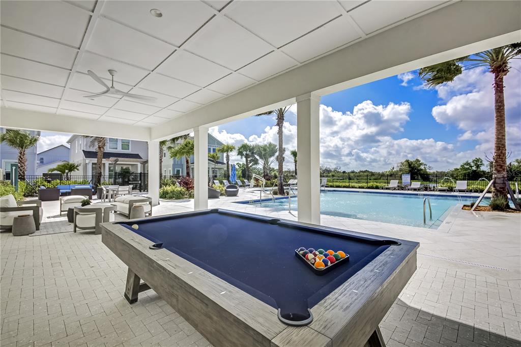 A pool table sits on a covered patio overlooking an outdoor swimming pool and palm trees — 9131 WALCOTT LANE, LAKEWOOD RANCH, FL