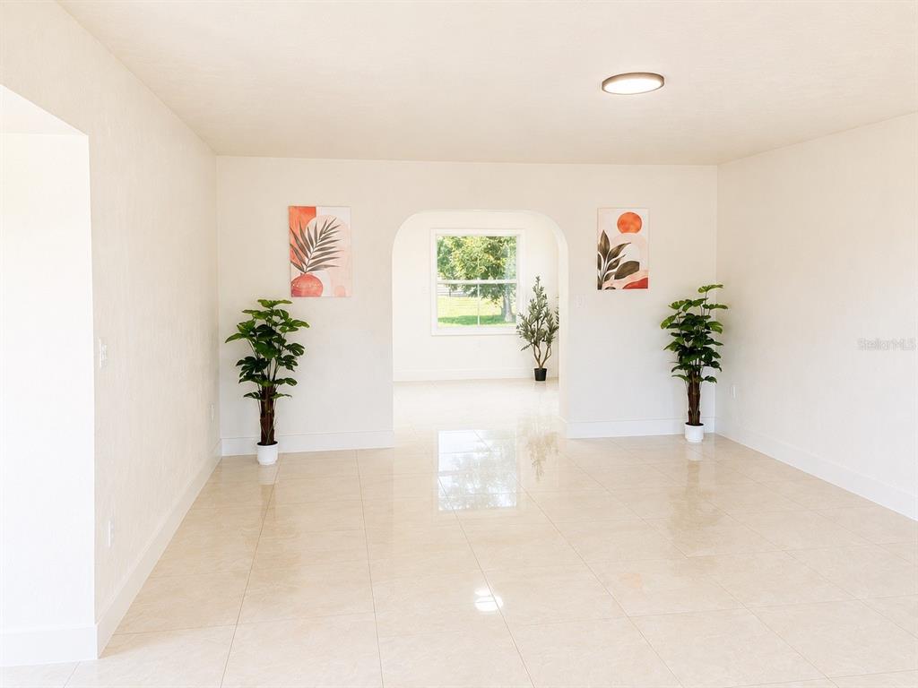 A bright, empty room features light-colored tile flooring, white walls, and an arched doorway — 21330 MEEHAN AVENUE, PORT CHARLOTTE, FL