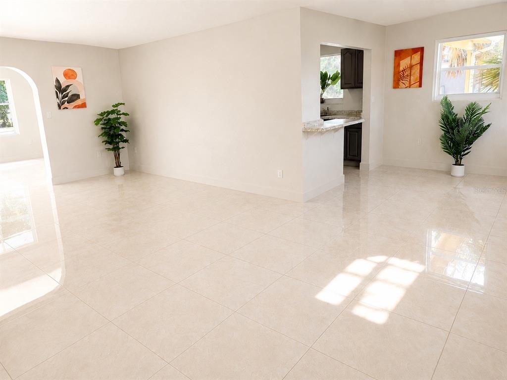 An open-concept living area features light-colored tile flooring, white walls, and a kitchen pass-through — 21330 MEEHAN AVENUE, PORT CHARLOTTE, FL