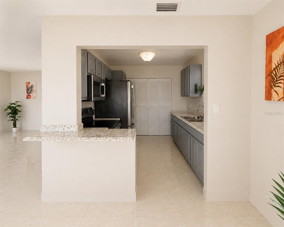 A kitchen with gray cabinets, stainless steel appliances, and a granite-topped breakfast bar — 21330 MEEHAN AVENUE, PORT CHARLOTTE, FL