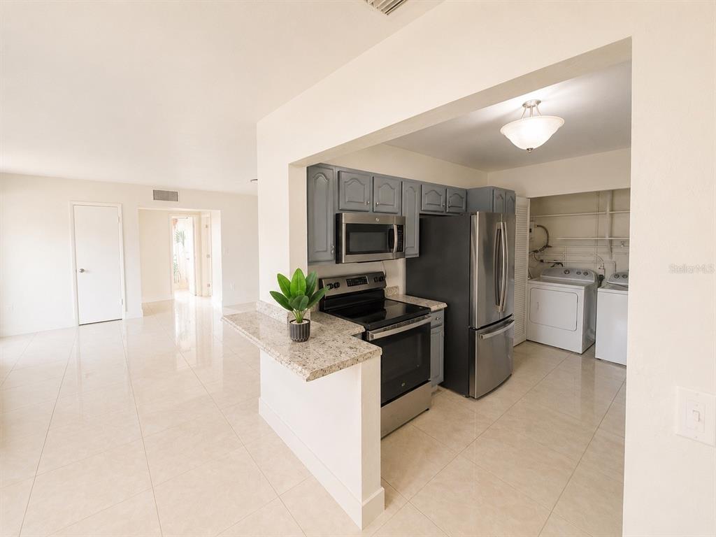 A kitchen with gray cabinets, stainless steel appliances, and a granite breakfast bar — 21330 MEEHAN AVENUE, PORT CHARLOTTE, FL