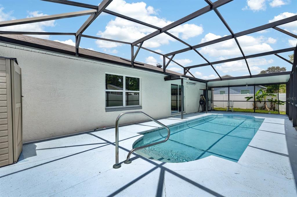 A swimming pool sits on a concrete patio enclosed by a screened-in lanai structure — 20 LAKE MEADOW WAY, ORMOND BEACH, FL