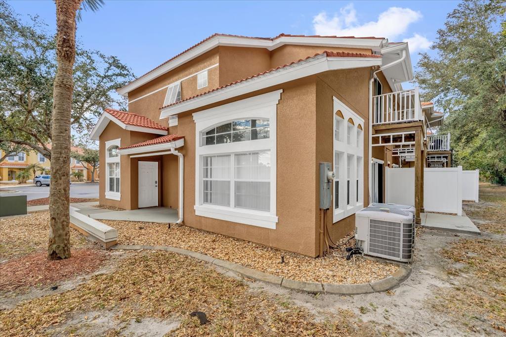 A two-story tan stucco townhouse with a red tile roof and a side balcony — 1001 PARK RIDGE CIRCLE, KISSIMMEE, FL