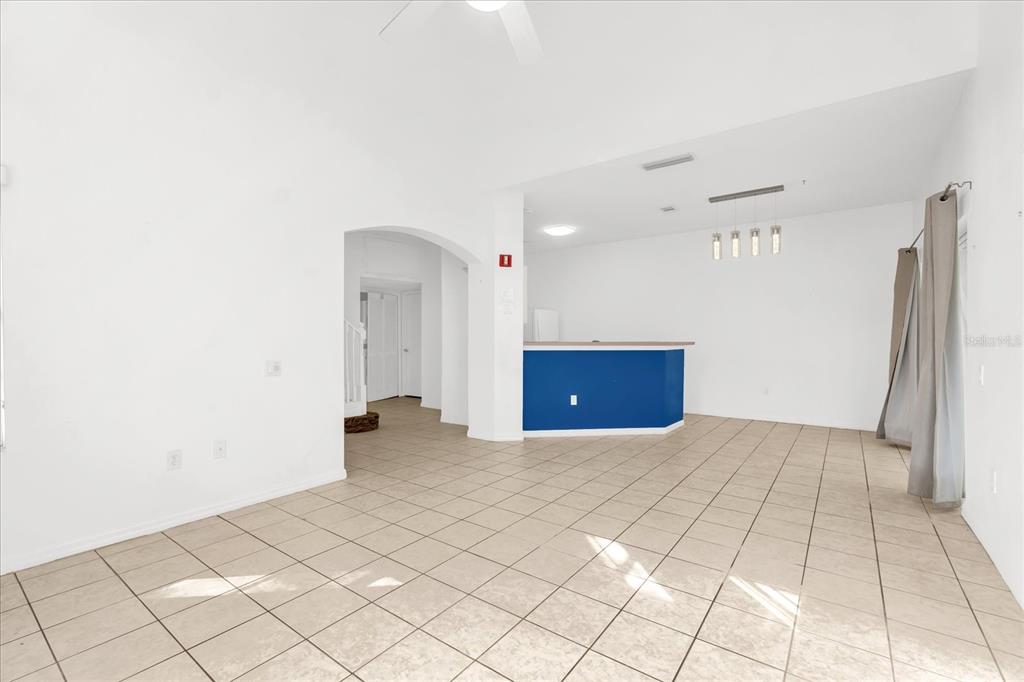 A bright, open-concept living area features beige tile flooring, white walls, and a blue kitchen island — 1001 PARK RIDGE CIRCLE, KISSIMMEE, FL