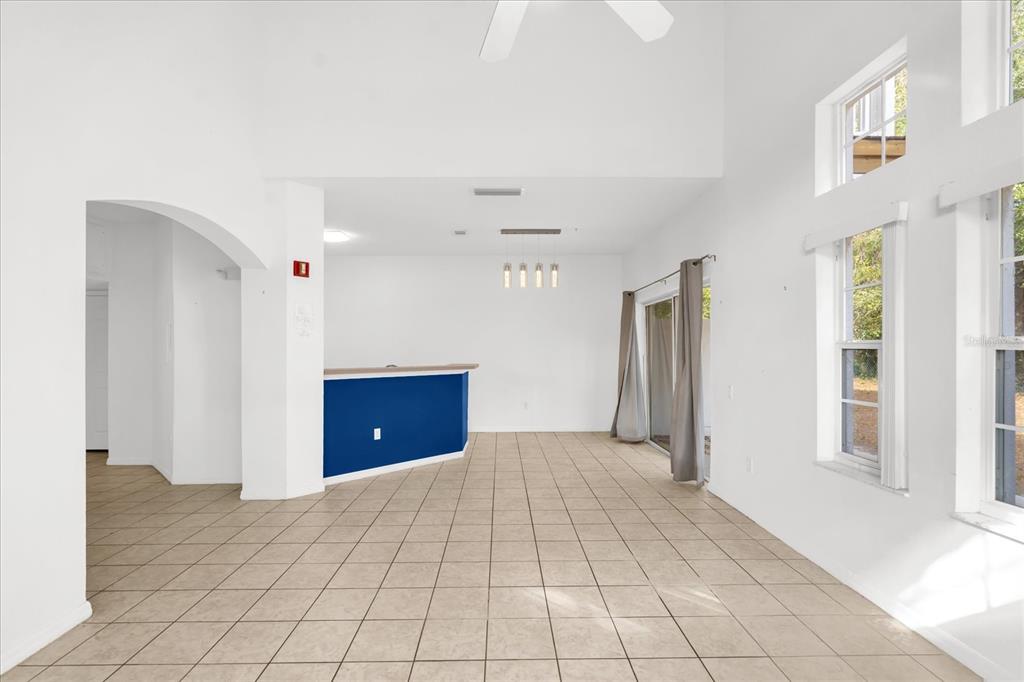 An open-concept living area features white walls, beige tile flooring, and a blue kitchen island — 1001 PARK RIDGE CIRCLE, KISSIMMEE, FL
