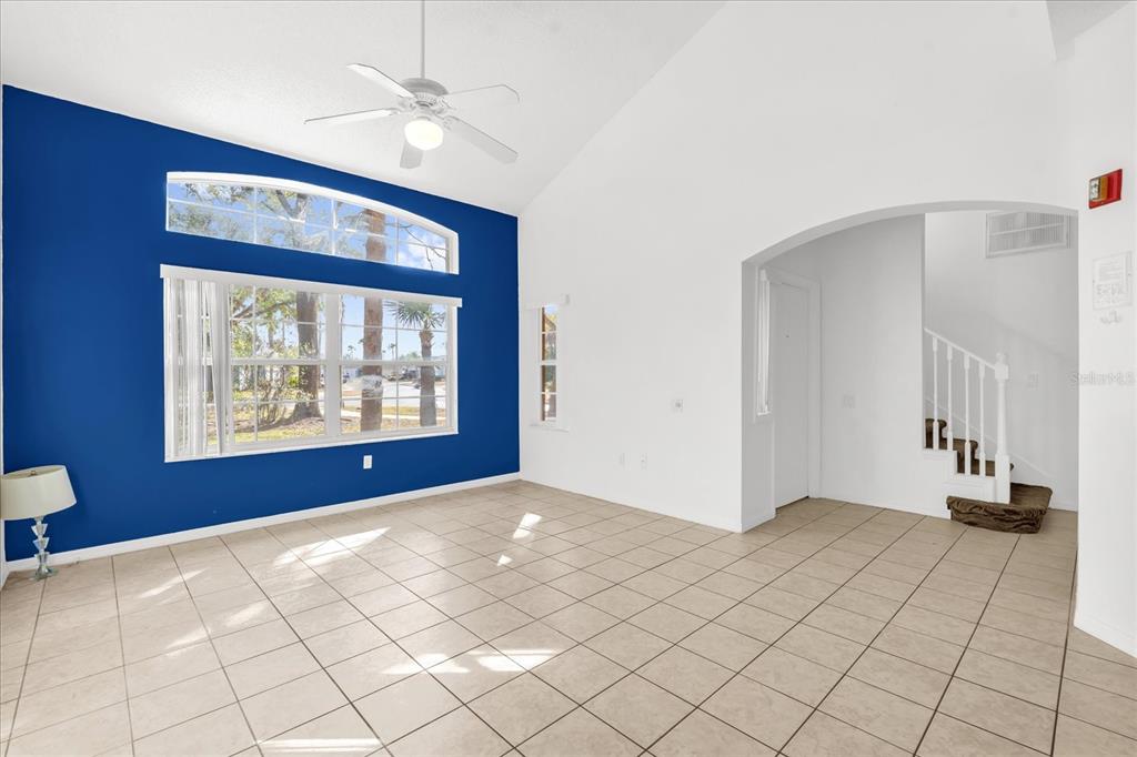 A living room with tile floors, a vaulted ceiling, and a blue accent wall — 1001 PARK RIDGE CIRCLE, KISSIMMEE, FL