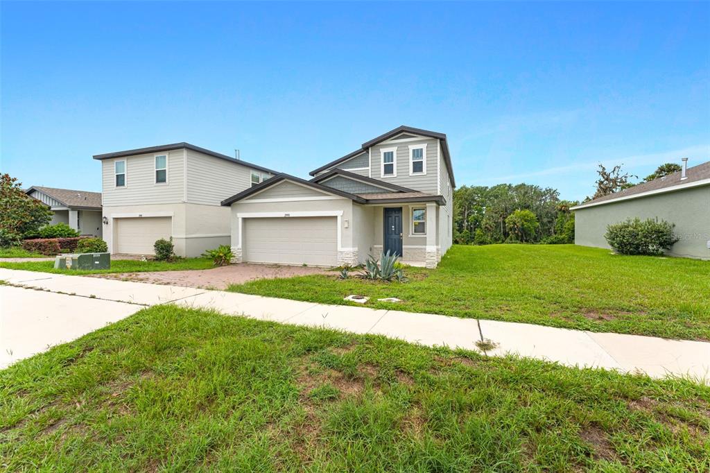 A two-story suburban house with a beige exterior, a two-car garage, and a grassy yard — 29991 ANAHID DRIVE, LEESBURG, FL