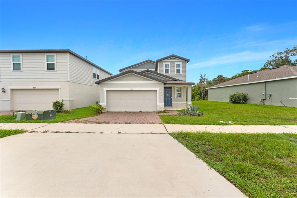 The exterior of a two-story house features a blue front door, stone accents, and siding — 29991 ANAHID DRIVE, LEESBURG, FL
