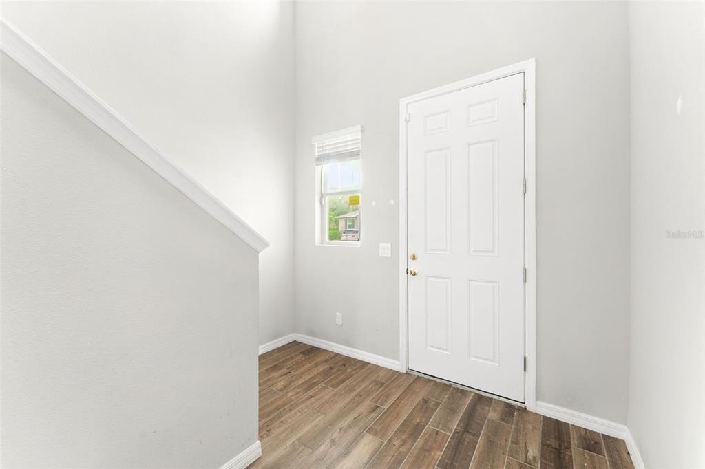 An entryway with light gray walls, wood-look flooring, a white door, and a small window — 29991 ANAHID DRIVE, LEESBURG, FL