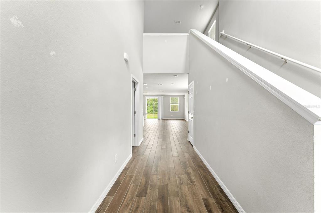 A bright entryway features wood-look tile flooring, a high ceiling, and a staircase with railing — 29991 ANAHID DRIVE, LEESBURG, FL