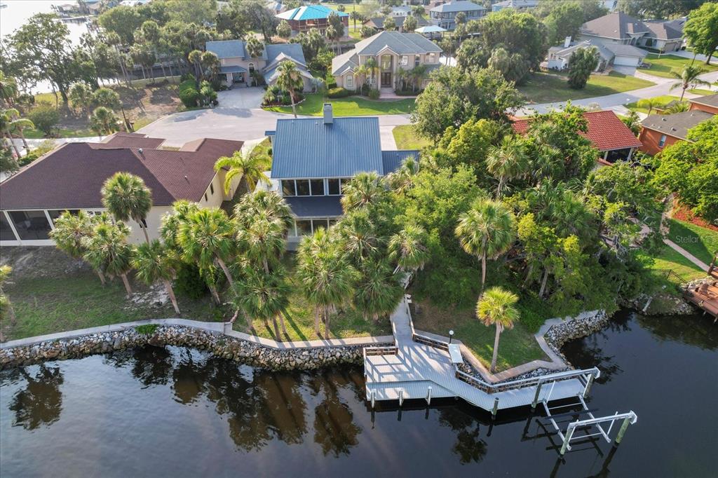 An aerial view shows a waterfront house with a metal roof, dock, and palm trees — 5259 S STETSON POINT DRIVE, HOMOSASSA, FL