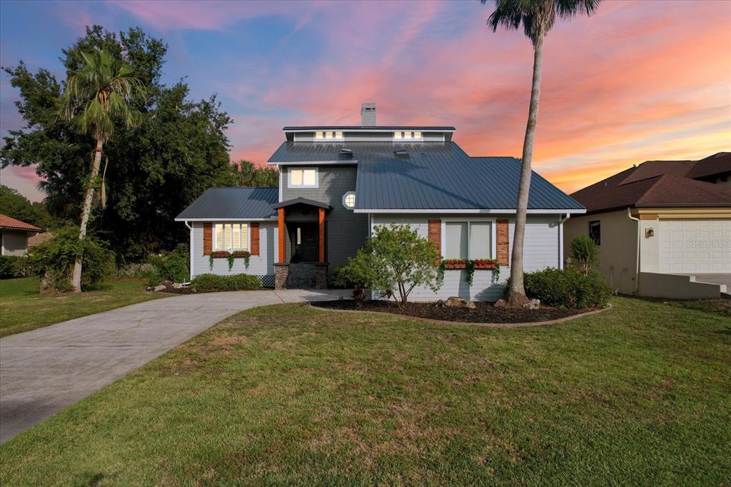 A two-story house with a metal roof, gray siding, and a concrete driveway at sunset — 5259 S STETSON POINT DRIVE, HOMOSASSA, FL