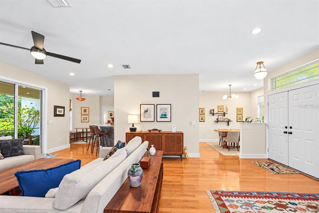 A living room with hardwood floors, a sofa, a console table, and an adjacent dining area — 2013 MACARTHUR COURT, DUNEDIN, FL