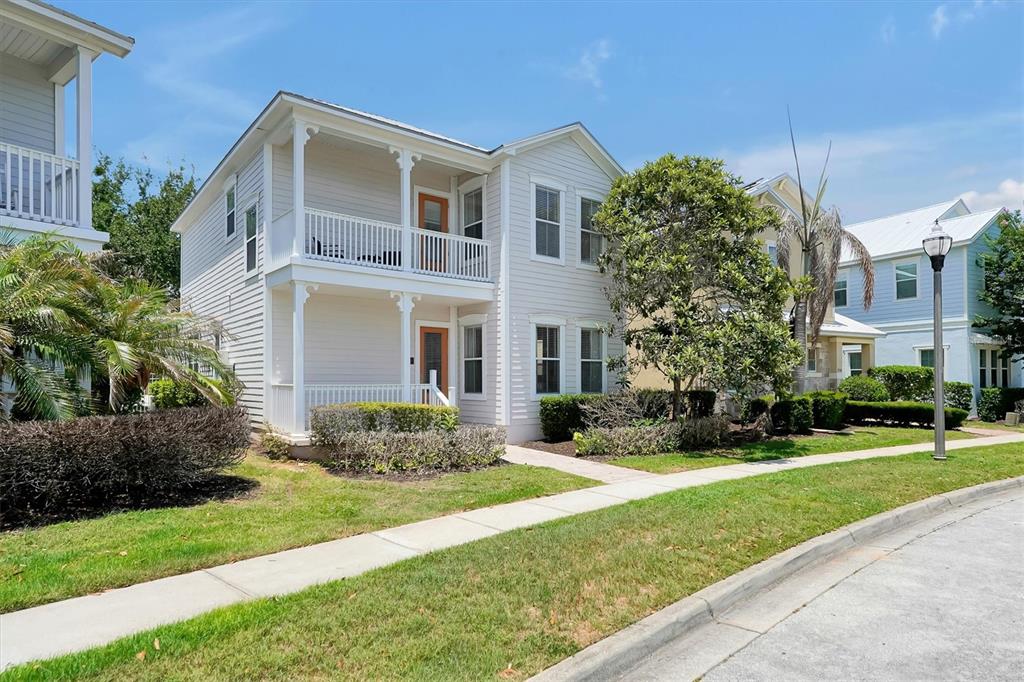 A two-story house with white siding, a front porch, and a balcony under a blue sky — 7768 LINKSIDE LOOP, REUNION, FL