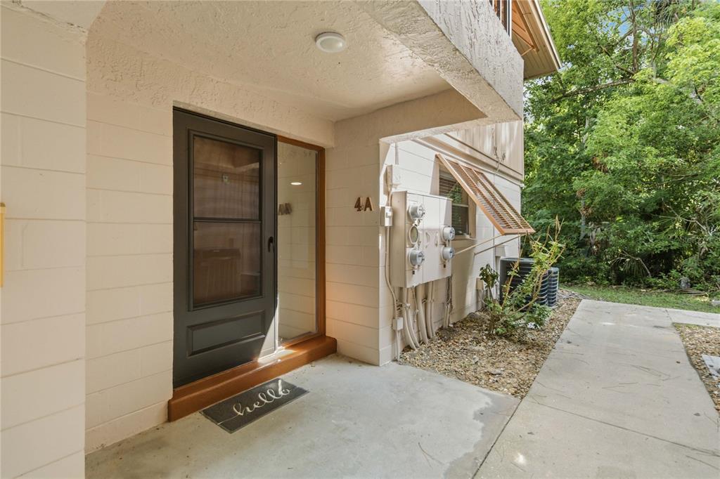 An entryway features a white front door with a sidelight, louvered closet doors, and tile flooring — 164 PERIMETER DRIVE UNIT 4A, DELTONA, FL