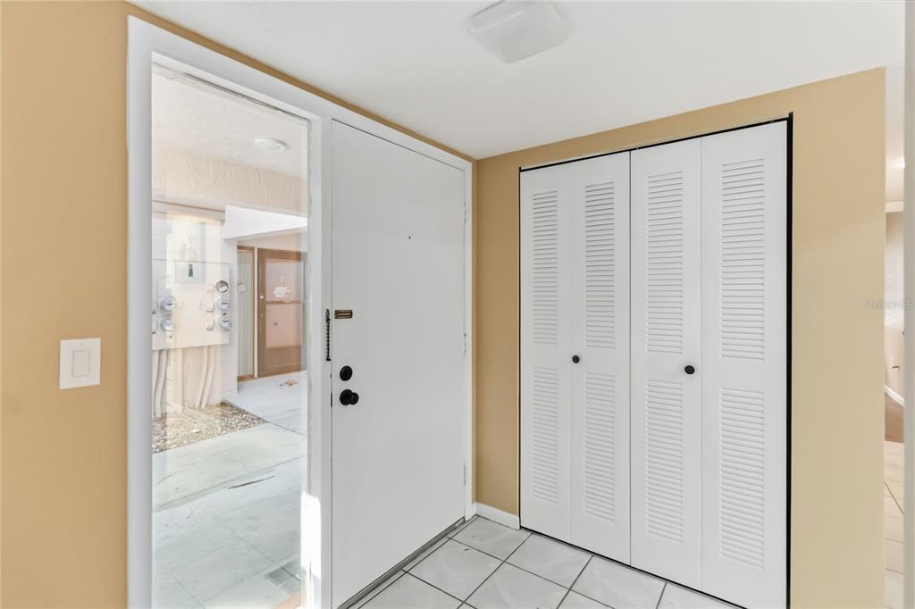 An empty living room features light wood-look flooring, beige walls, a ceiling fan, and sliding doors — 164 PERIMETER DRIVE UNIT 4A, DELTONA, FL