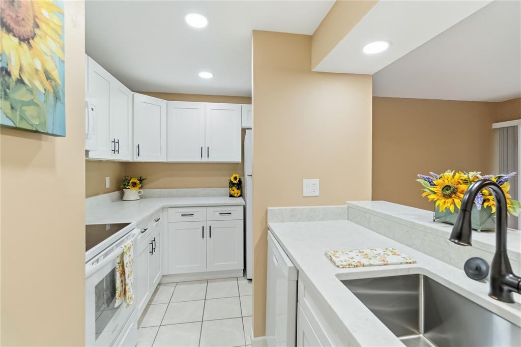 A living room with wood-look flooring, a ceiling fan, and an opening to a kitchen — 164 PERIMETER DRIVE UNIT 4A, DELTONA, FL