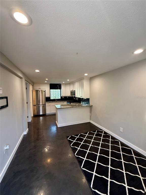 A kitchen with white cabinets, stainless steel appliances, and a peninsula overlooks a dining area — 3528 5TH AVENUE N, ST PETERSBURG, FL