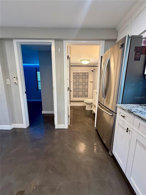 A kitchen with concrete floors leads to a bathroom and a bedroom with blue lighting — 3528 5TH AVENUE N, ST PETERSBURG, FL
