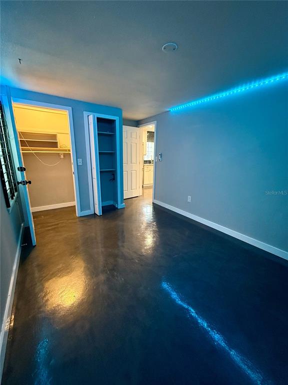 A room with dark concrete floors, blue LED accent lighting, and two open closet doorways — 3528 5TH AVENUE N, ST PETERSBURG, FL