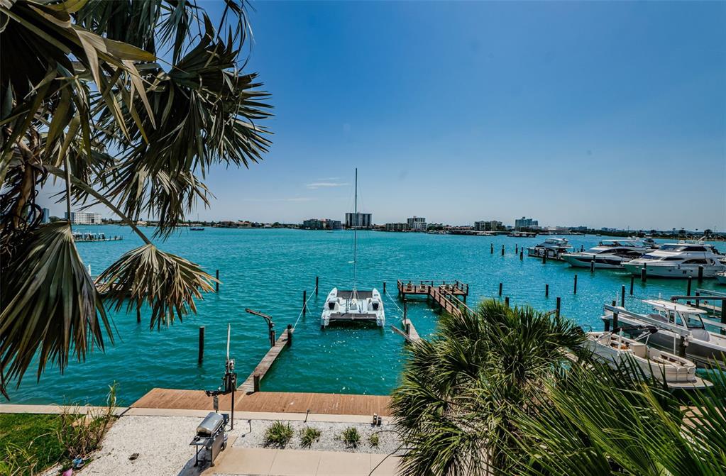 A view of a boat dock and turquoise water from a waterfront patio with palm trees — 479 E SHORE DR UNIT 8, CLEARWATER, FL