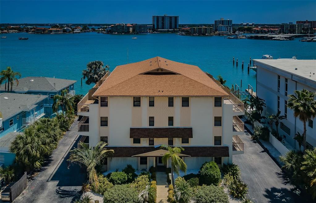 An aerial view shows a multi-story apartment building with a brown roof near the water — 479 E SHORE DR UNIT 8, CLEARWATER, FL