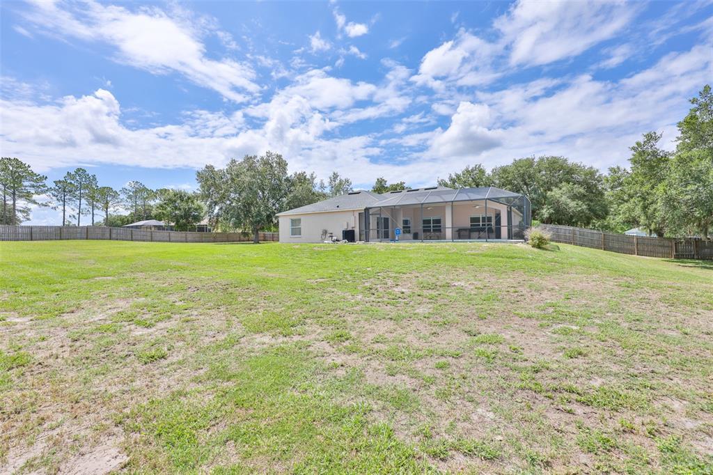 A large, fenced backyard features a single-story house with a screened-in pool enclosure — 10234 BLOOMFIELD HILLS DRIVE, SEFFNER, FL