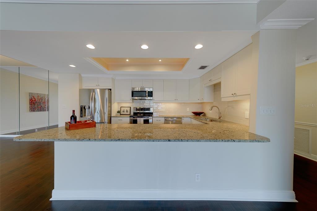 A kitchen with granite countertops, white cabinetry, stainless steel appliances, and a breakfast bar — 8 BELLEVIEW BOULEVARD UNIT 308, BELLEAIR, FL