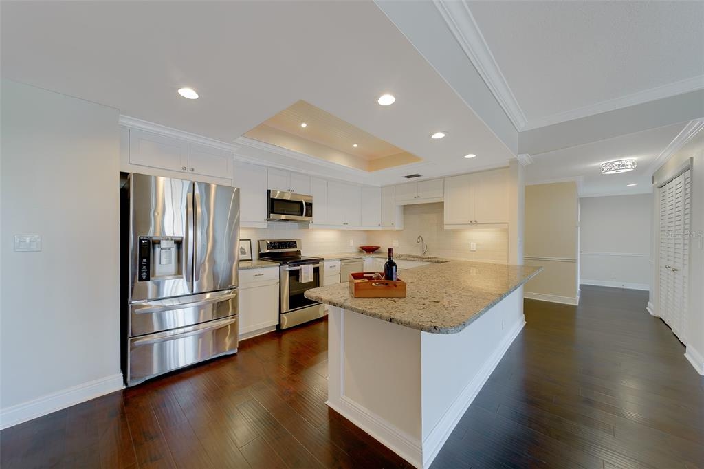 A kitchen with white cabinets, stainless steel appliances, granite countertops, and dark hardwood flooring — 8 BELLEVIEW BOULEVARD UNIT 308, BELLEAIR, FL