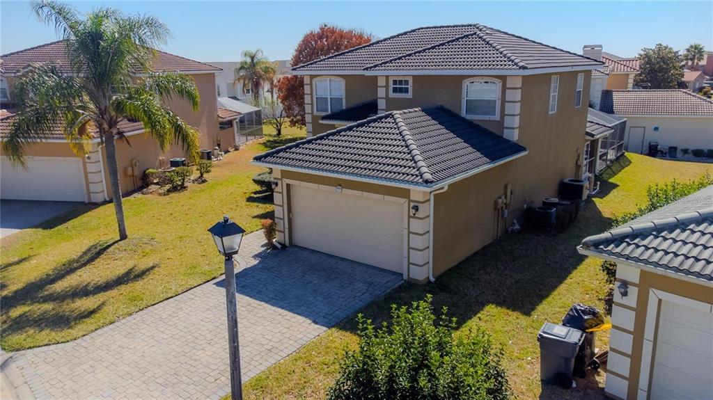 An elevated exterior view of a two-story tan house with a paved driveway and garage — 416 VISTA LOOP, DAVENPORT, FL