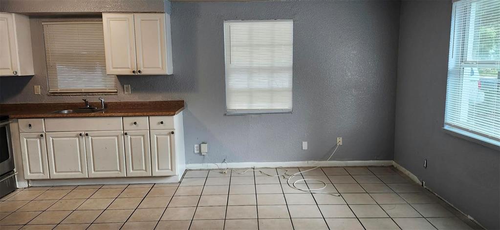 A kitchen with white cabinets, a brown countertop, tiled flooring, and gray walls — 9809 N JASMINE AVENUE UNIT B, TAMPA, FL