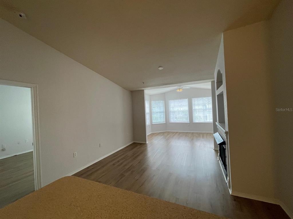 An empty living room features light wood-look flooring, a fireplace, and a bay window — 3379 S KIRKMAN ROAD UNIT 1032, ORLANDO, FL