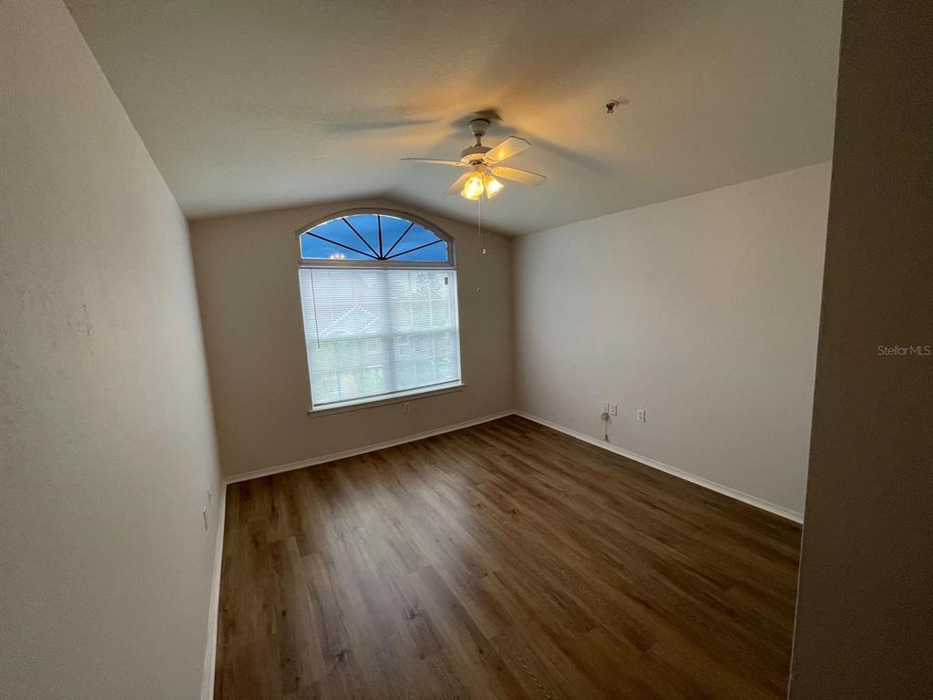 An empty bedroom features light-colored walls, wood-look flooring, a ceiling fan, and an arched window — 3379 S KIRKMAN ROAD UNIT 1032, ORLANDO, FL