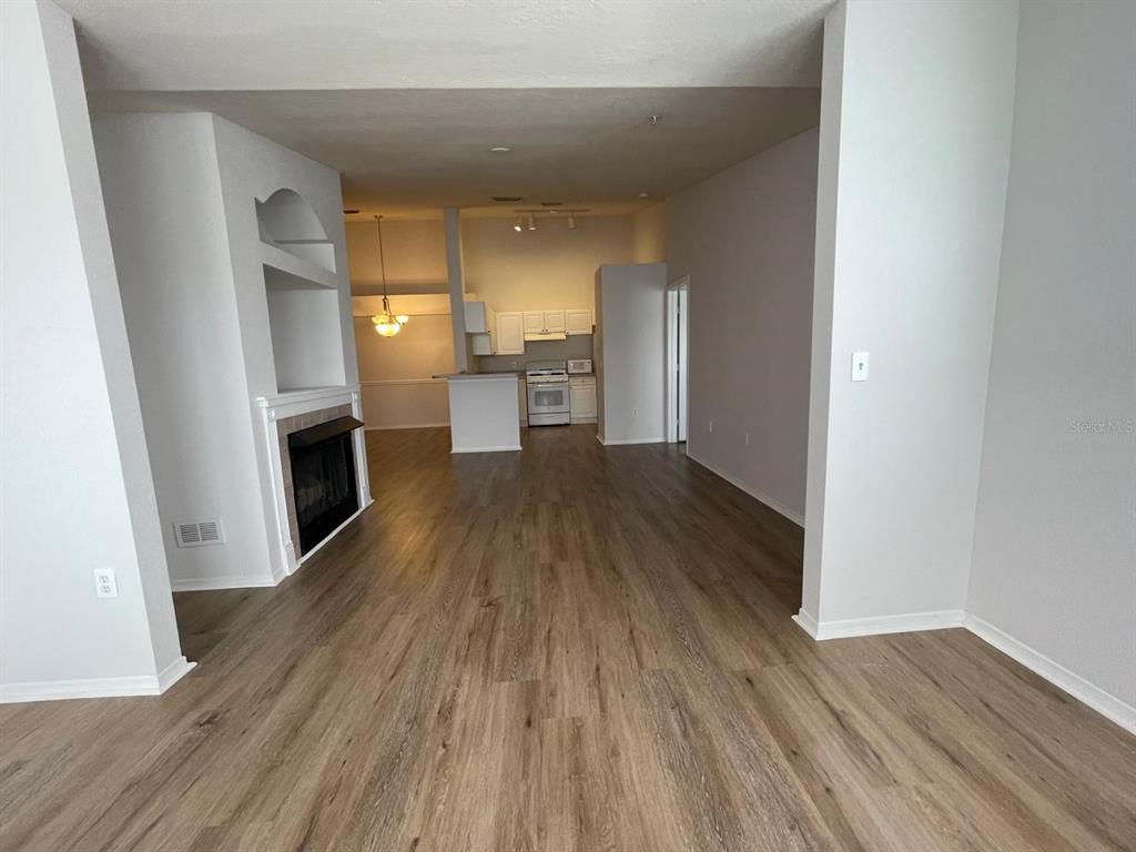 An open-concept living area features wood-look flooring, a fireplace, and a kitchen in the background — 3379 S KIRKMAN ROAD UNIT 1032, ORLANDO, FL