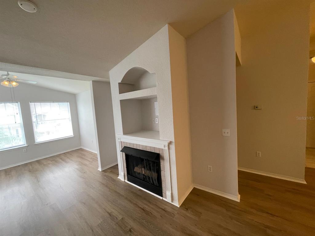 A living room features light wood-look flooring, a fireplace, and built-in shelving — 3379 S KIRKMAN ROAD UNIT 1032, ORLANDO, FL