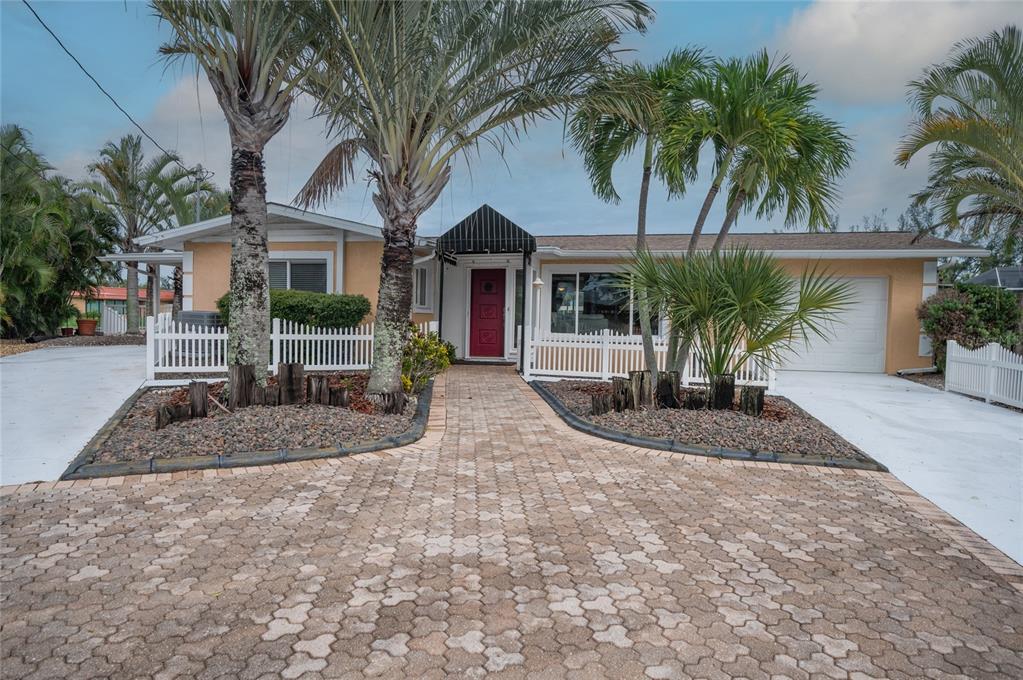 A covered patio overlooks a swimming pool and spa with a canal view in the background — 4223 ROYAL PALM DRIVE, BRADENTON, FL