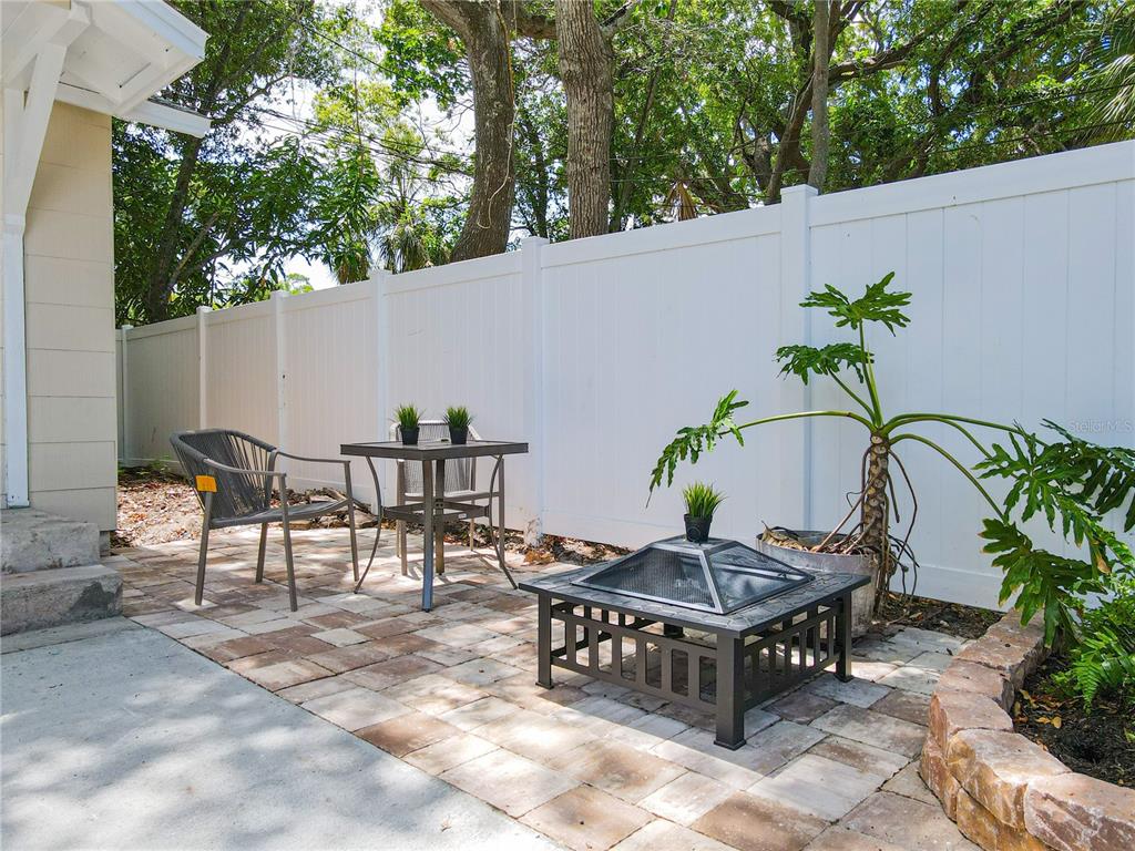 A patio with a fire pit, a small table, two chairs, and a white privacy fence — 609 N OSCEOLA AVENUE UNIT A, CLEARWATER, FL